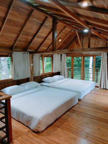 two beds in a room with wooden ceilings and windows at Villa Da- Hee in Bandungan