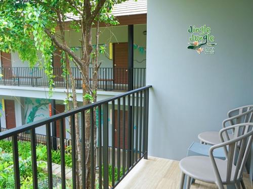 a balcony with two chairs and a tree at JINGLE JUNGLE RESORT KHAOYAI in Mu Si
