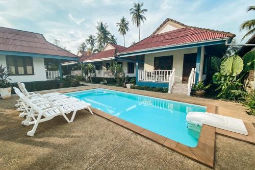 a swimming pool with two chairs and a house at House No.2 Village in Krabi