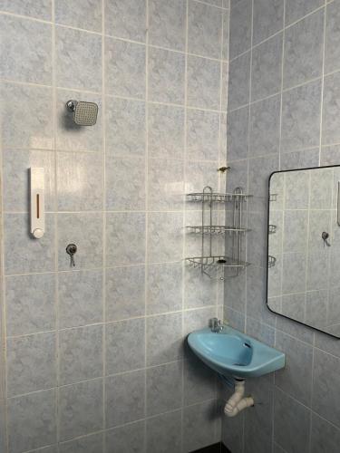een badkamer met een blauwe wastafel en een spiegel bij Homestay Dyzas in Batu-grotten