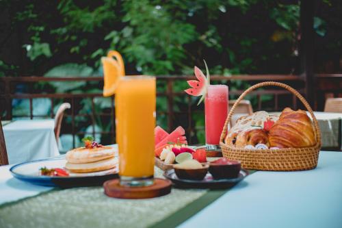 una mesa con un plato de comida y dos vasos de zumo de naranja en The Sebali Resort en Ubud