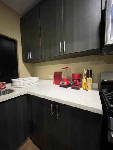 a kitchen with black cabinets and a white counter top at Lomeli’s Home, 5 minutos del Tunco in La Libertad