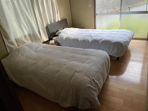 two beds in a hotel room with white sheets at 晋shin宇治浦田 in Uji