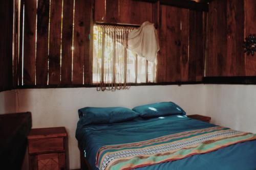 a bed in a room with wooden walls at Garden Cabins in Zipolite