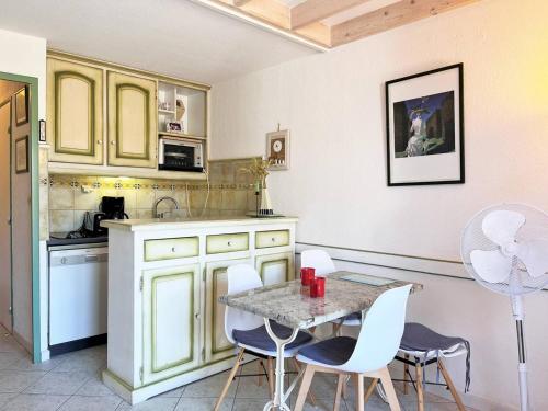 une cuisine avec une table et des chaises et une cuisine avec des armoires jaunes dans l'établissement Duplex familial avec terrasse, proche plage, parking privé - 4 couchages, Le Lavandou - FR-1-251-541, au Lavandou