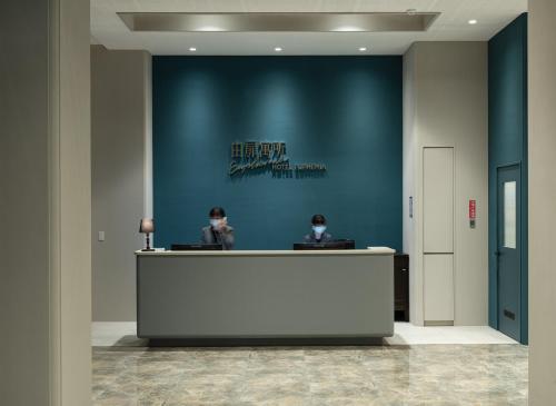 two people sitting at a reception desk in a lobby at Hotel Euphemia in Taichung