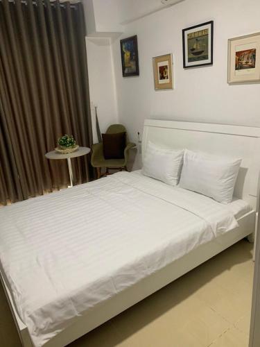 a bedroom with a white bed with a table and a chair at The Everich Infinity 290 ADV in Ho Chi Minh City