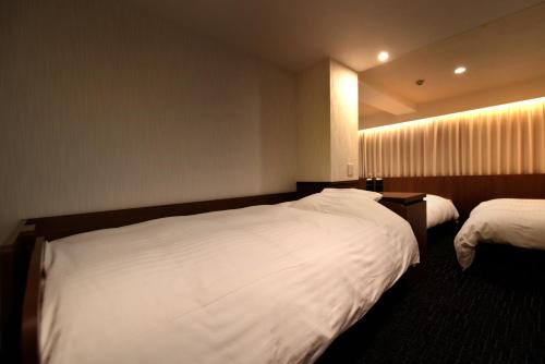 a hotel room with two beds with white sheets at ホテルプラタナス新横浜 in Yokohama