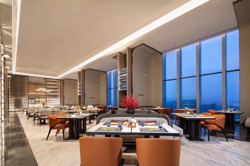 a restaurant with tables and chairs and large windows at Crowne Plaza Jinan Runhua by IHG in Jinan