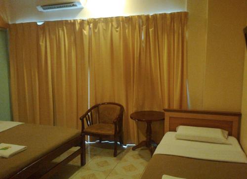 a bedroom with a bed and a chair and a window at Hotel Western in Sandakan