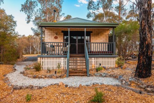 a tiny house in the woods with a porch at Maya Sanctuary in Little Hartley