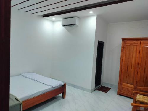 1 dormitorio con 1 cama y armario de madera en Khách sạn Gia Nghiêm 2, en Ấp Cái Giá