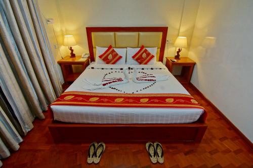 1 dormitorio con 1 cama y zapatillas en el suelo en Gold Yadanar Hotel, en Mandalay