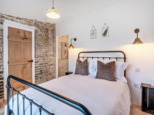 a bedroom with a bed and a brick wall at The Ostlers Cottage in Sleaford
