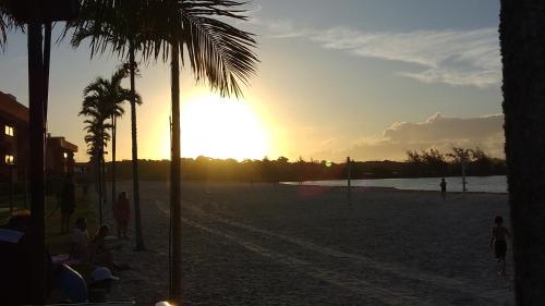 a group of people on a beach with the sunset at Golden Lake Apart Hotel Arraial do Cabo RJ A&J 2 in Arraial do Cabo