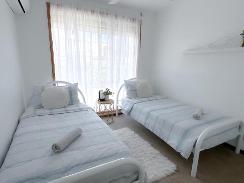 two beds in a white room with a window at Coastal Springs - PET FRIENDLY & 200m To Beach! in Clifton Springs