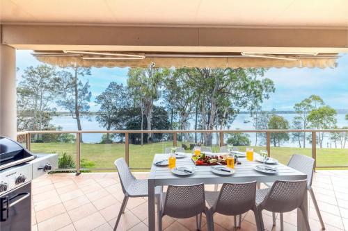 a table and chairs on a patio with a view of the ocean at Danalene, 44a Danalene Pde - stunning waterfront property with Air Con, WI-FI, Double Lock Up Garage & Boat Parking in Corlette