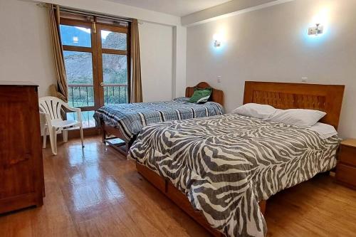 1 dormitorio con 2 camas y ventana en QHAPAQ WASI, en Cusco