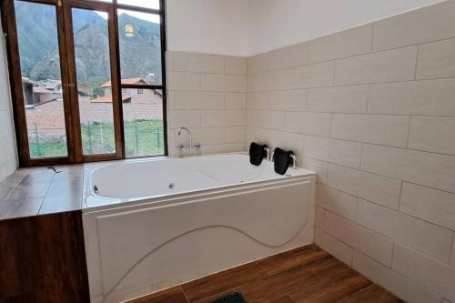 una gran bañera blanca en una habitación con ventana en QHAPAQ WASI, en Cusco