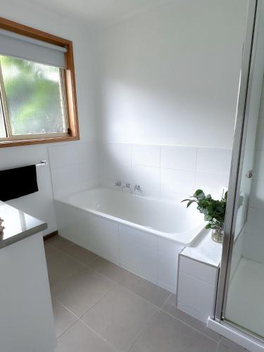 a white bathroom with a tub and a window at Coastal Springs - PET FRIENDLY & 200m To Beach! in Clifton Springs