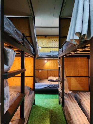 3 Etagenbetten in einem Zimmer mit grünem Gras in der Unterkunft The 10 club hostel in Thongsala