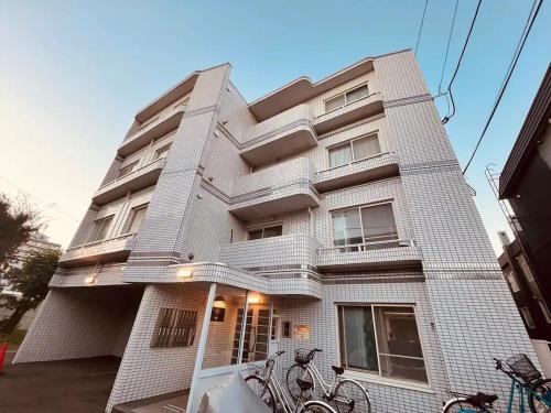 a building with bikes parked in front of it at HS平岸 HSHiraghishi in Minami-jūichijō