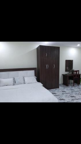 a bedroom with a large bed and a wooden cabinet at 6A Resort LTD in Owerri