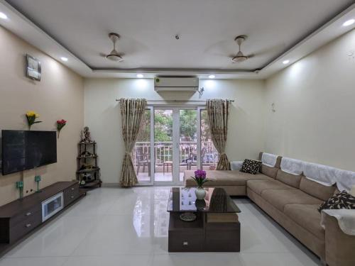 a living room with a couch and a tv at Soul House_4.5 BHK Apartment in Ahmedabad