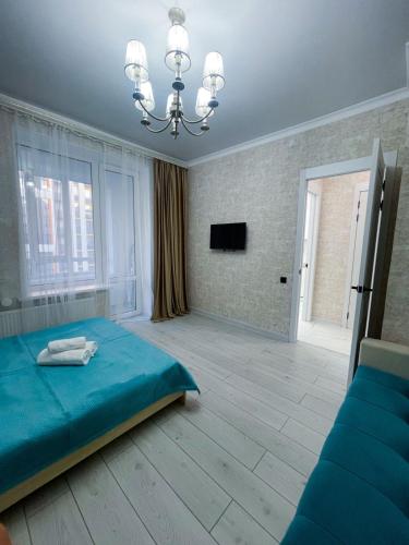 Un dormitorio con una cama azul y una lámpara de araña. en Сдам однокомнатную квартиру по Туран 55/6, en Taldykolʼ