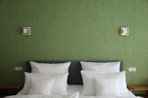 a bed with white pillows and a green wall at Luisenhof in Geisfeld