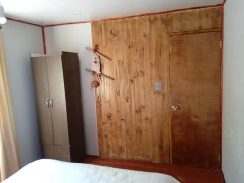 1 dormitorio con puerta de madera junto a la cama en Cabañas Rústicas Pucon, en Pucón