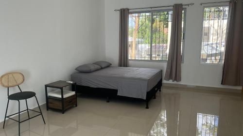 um quarto com uma cama, uma cadeira e janelas em Hotel Bella em Tamarindo