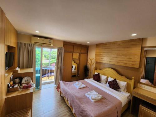 パトンビーチにあるAlaita Hostel Patongの大型ベッド1台、テレビが備わるホテルルームです。