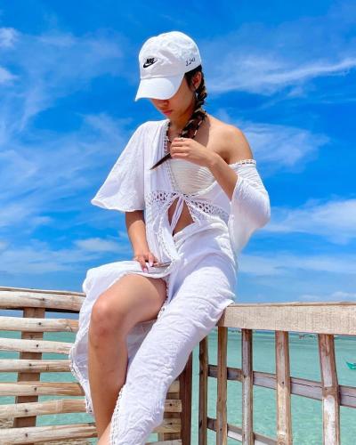 a woman in a white dress sitting on a fence at Bahai ni Jhane in Calatagan