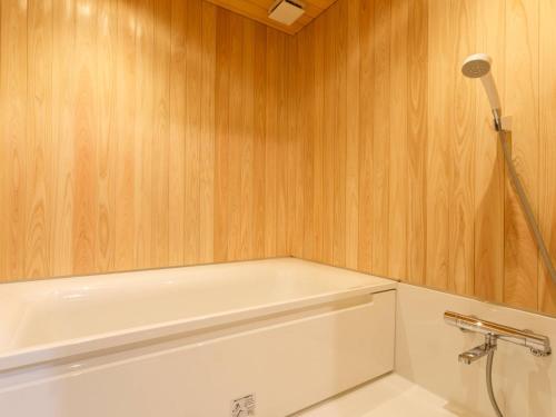 a bathroom with a white toilet and wooden walls at RITA Izumo Sagiura in Izumo