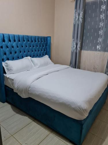 a bed with a blue headboard in a room at La Ribera Cosy Homes in Bomet