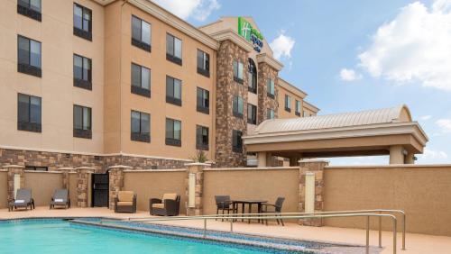 a hotel with a pool and chairs and a building at Holiday Inn Express & Suites Midland South I-20 by IHG in Midland