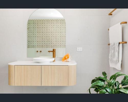 ein Bad mit einem Waschbecken und einem Spiegel in der Unterkunft Ocean Lake Oasis in Wamberal