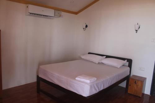 a bedroom with a bed with white sheets and pillows at Nikhil's Beach Cottages in Canacona