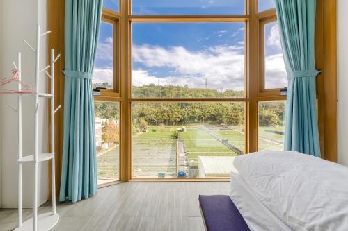 a bedroom with a large window looking out at a field at Quan Ming B&B in Dahu