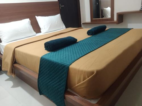 a large bed with two blue pillows on it at Mayura residency in Palani
