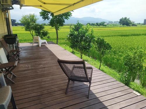 a wooden deck with two chairs and a view of a field at 小k柯林民宿 最多18人烤肉聚會 親子遊戲區 寵物友善 庭院 電動麻將桌 in Yilan City
