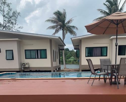 una villa con piscina con tavolo e ombrellone di Care Villa Koh Phangan a Ko Phangan