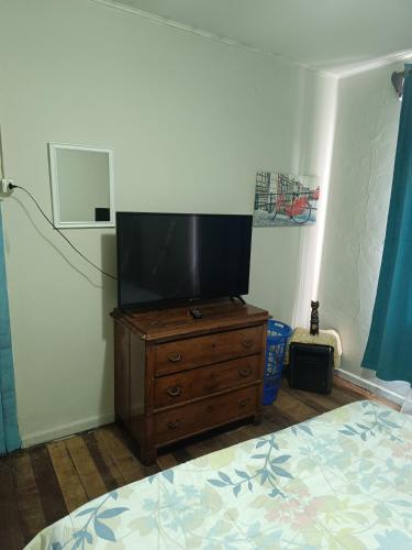 1 dormitorio con TV en una cómoda de madera en Habitación grande céntrica, en La Serena