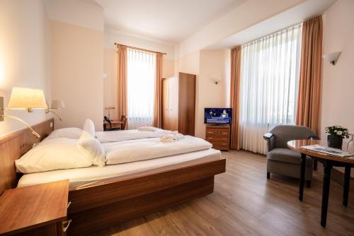 a hotel room with a large bed and a desk at Alpenstadthotels in Bad Reichenhall