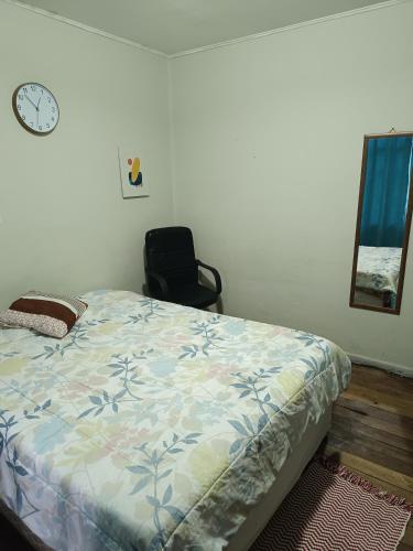 1 dormitorio con 1 cama, 1 silla y 1 reloj en Habitación grande céntrica, en La Serena