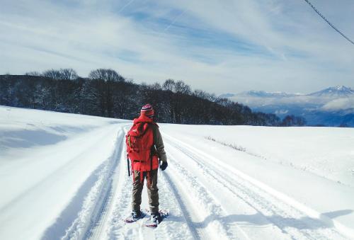 a person is standing on a snow covered road at Yamane in Nozawa Onsen