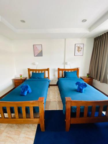 two beds in a room with blue sheets and blue pillows at BT hotel Kata Beach in Kata Beach