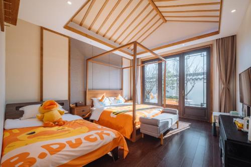 - une chambre avec 2 lits et un ours en peluche assis sur le lit dans l'établissement Yangzhou Mangdao Garden Resort, à Yangzhou