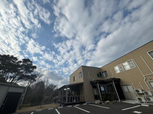 a building with a cloudy sky in a parking lot at SWELL in Hyuga